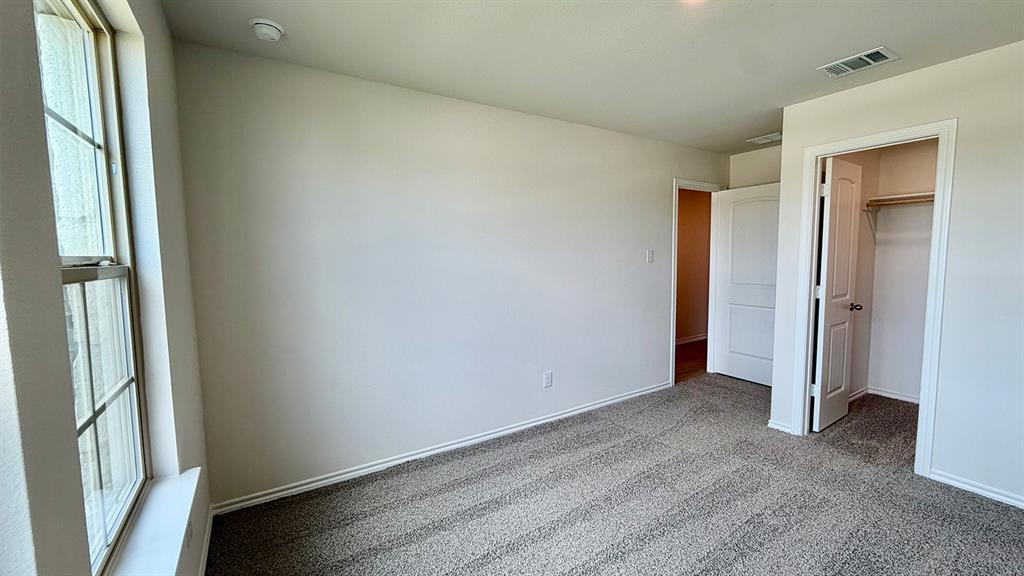 2003 Reveille Way Terrell, TX 75160 - Photo 18 of 25 Carpeted interior room featuring a large window, neutral paint, white trim, and a closet with a bi-fold door