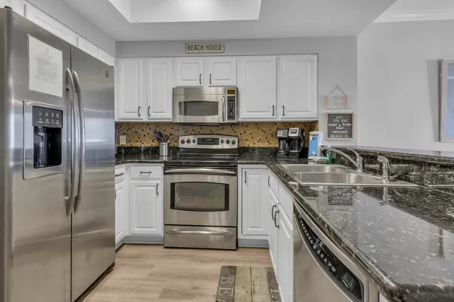 a kitchen with stainless steel appliances granite countertop a stove a microwave and white cabinets