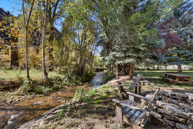 667 North Rapid Creek Road Inkom, ID 83245 - Photo 23 of 29 Stream-side setting featuring a natural rock fire pit, wooden Adirondack chairs, a picnic table, and mature trees