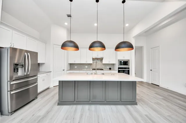 a kitchen with stainless steel appliances granite countertop a sink a stove and a wooden floors