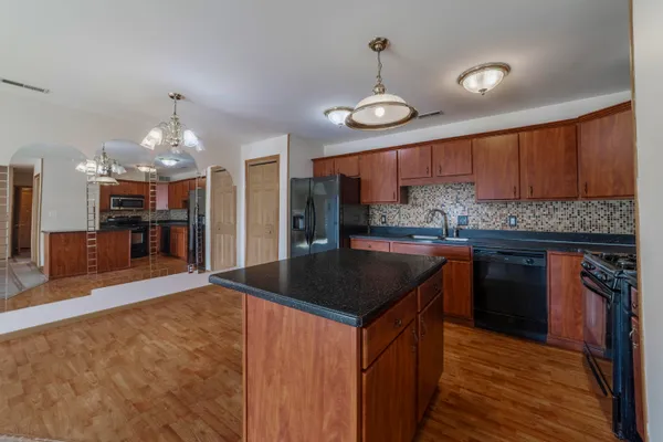 a kitchen with stainless steel appliances granite countertop a sink a stove and a wooden cabinets