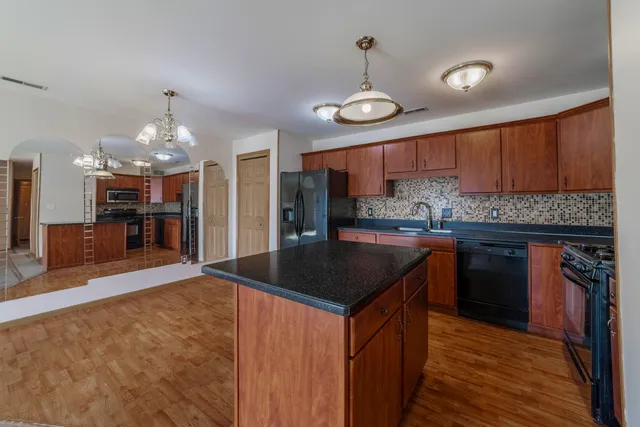 a kitchen with stainless steel appliances granite countertop a sink a stove and a wooden cabinets