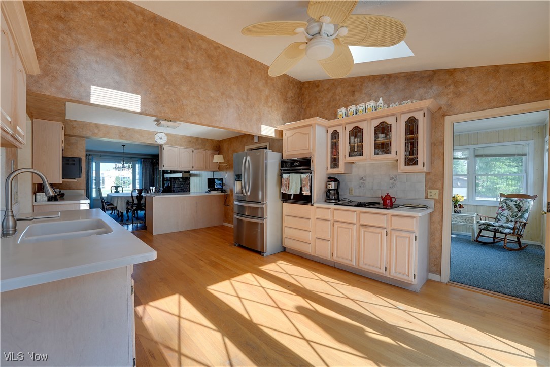 4939 Shankland Road Willoughby, OH 44094 - Photo 8 of 24 Kitchen with light wood-type flooring, stainless steel fridge with ice dispenser, oven, glass insert cabinets, and a towering ceiling