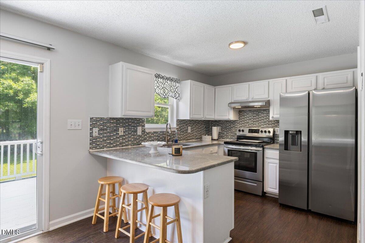 4708 River Boat Landing Court Raleigh, NC 27604 - Photo 23 of 61 a kitchen with stainless steel appliances granite countertop a stove a sink dishwasher a refrigerator and white cabinets with wooden floor