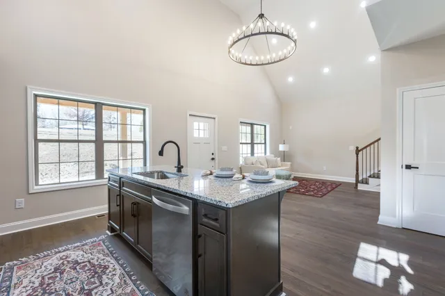 a kitchen with stainless steel appliances granite countertop a sink a stove and a wooden floors