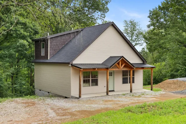 a view of a house with a yard and large tree