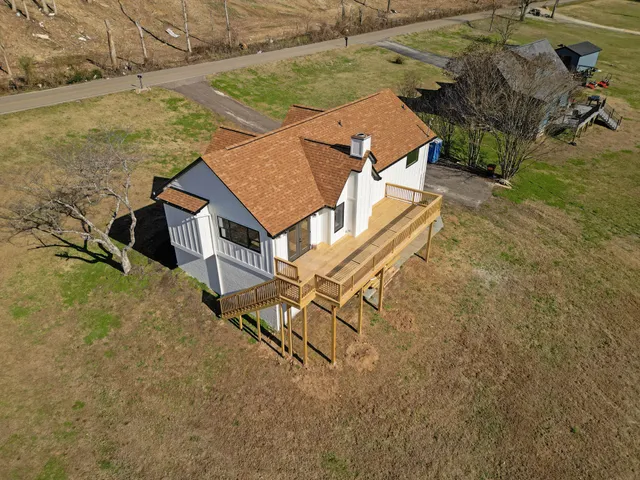 an aerial view of a house with swimming pool and large trees
