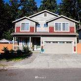 a view of a white house with large windows and a small yard