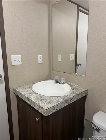 a bathroom with a granite countertop sink a mirror and a toilet