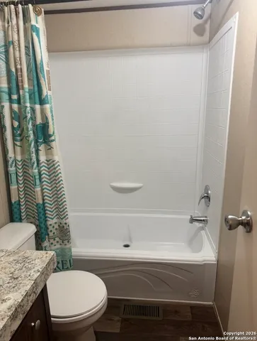 a bathroom with a granite countertop toilet and a bathtub