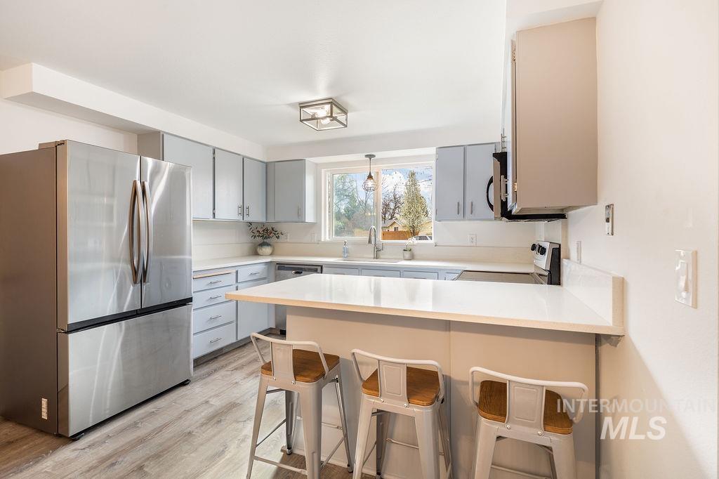 405 North 2nd Street Eagle, ID 83616 - Photo 6 of 39 Kitchen featuring stainless steel appliances, a kitchen bar, a peninsula, gray cabinetry, and light wood-type flooring