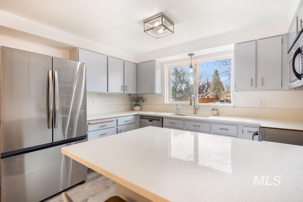 405 North 2nd Street Eagle, ID 83616 - Photo 9 of 39 Kitchen featuring stainless steel appliances, light wood-type flooring, gray cabinets, hanging light fixtures, and light stone countertops