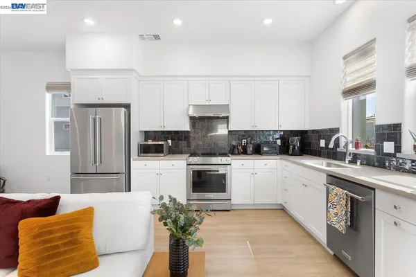 a kitchen with stainless steel appliances granite countertop a refrigerator a stove a sink and white cabinets