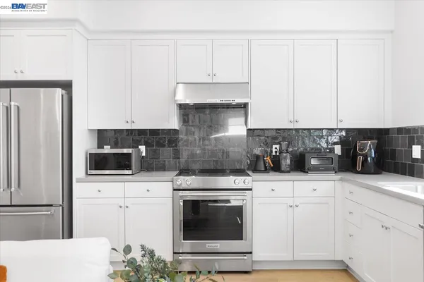 a kitchen with granite countertop white cabinets and stainless steel appliances