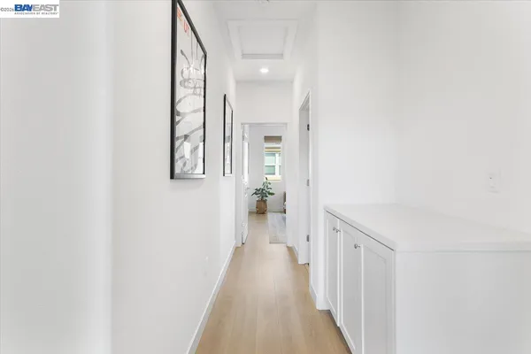 a view of a hallway with wooden floor and a bathroom