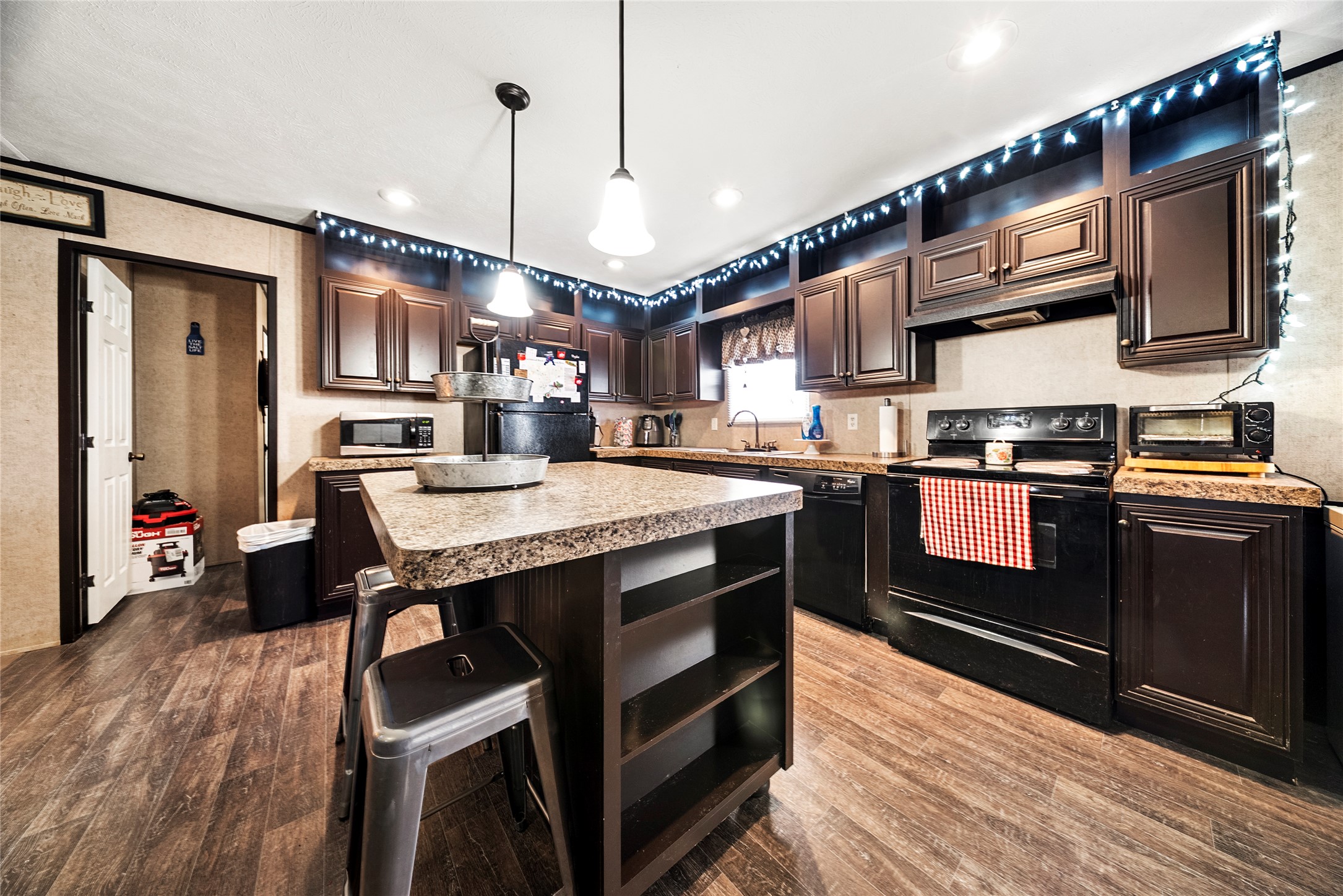 5101 County Road 463 Elgin, TX 78621 - Photo 22 of 38 Kitchen with black appliances, a breakfast bar, light countertops, a center island, and dark wood finish cabinetry.