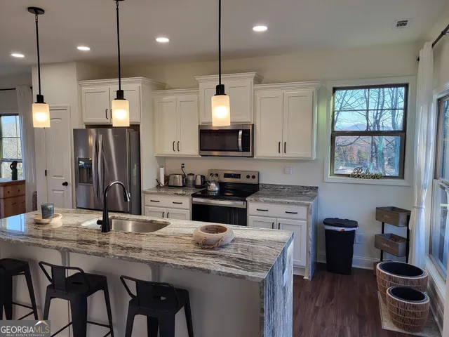 a kitchen with stainless steel appliances granite countertop a stove a sink dishwasher a refrigerator and a dining table with wooden floor