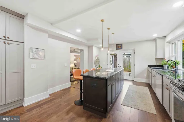 a kitchen with stainless steel appliances granite countertop a sink a stove and a wooden floors