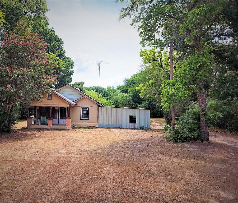 a view of a house with a yard and large trees