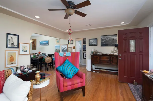 a living room with furniture kitchen view and a wooden floor