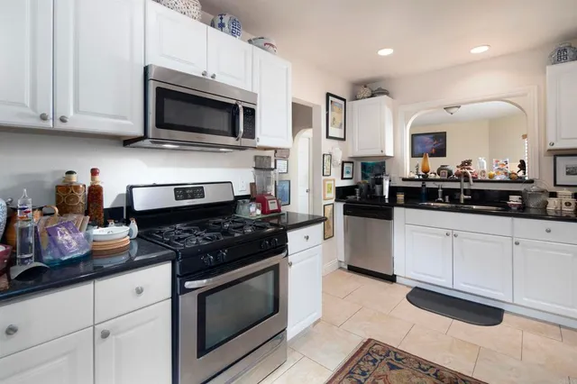 a kitchen with stainless steel appliances granite countertop white cabinets a stove a sink and dishwasher