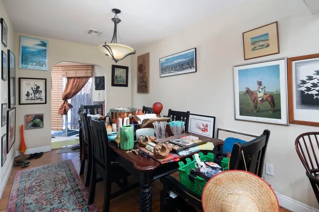 a living room with furniture a dining table and paintings on the wall