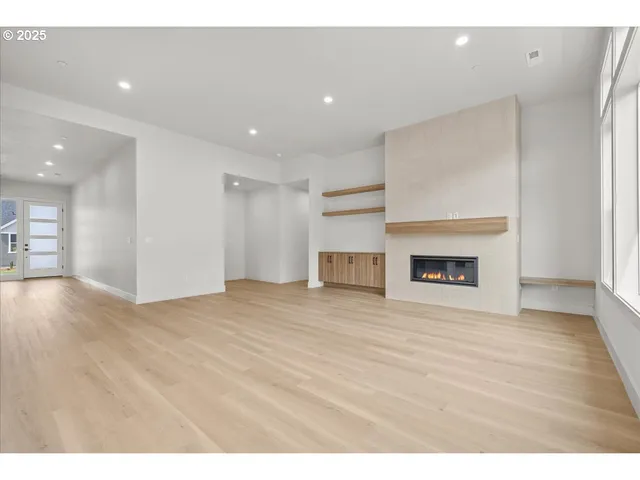 a view of an empty room with wooden floor and a fireplace