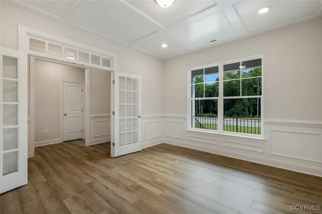 an empty room with wooden floor and windows
