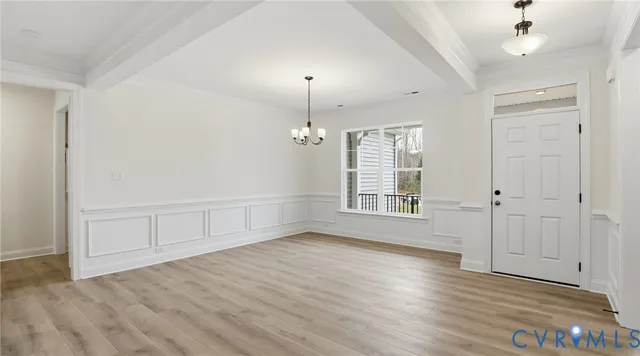 a view of an empty room with window and hardwood floor