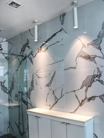 a bathroom with a granite countertop sink a mirror and shower
