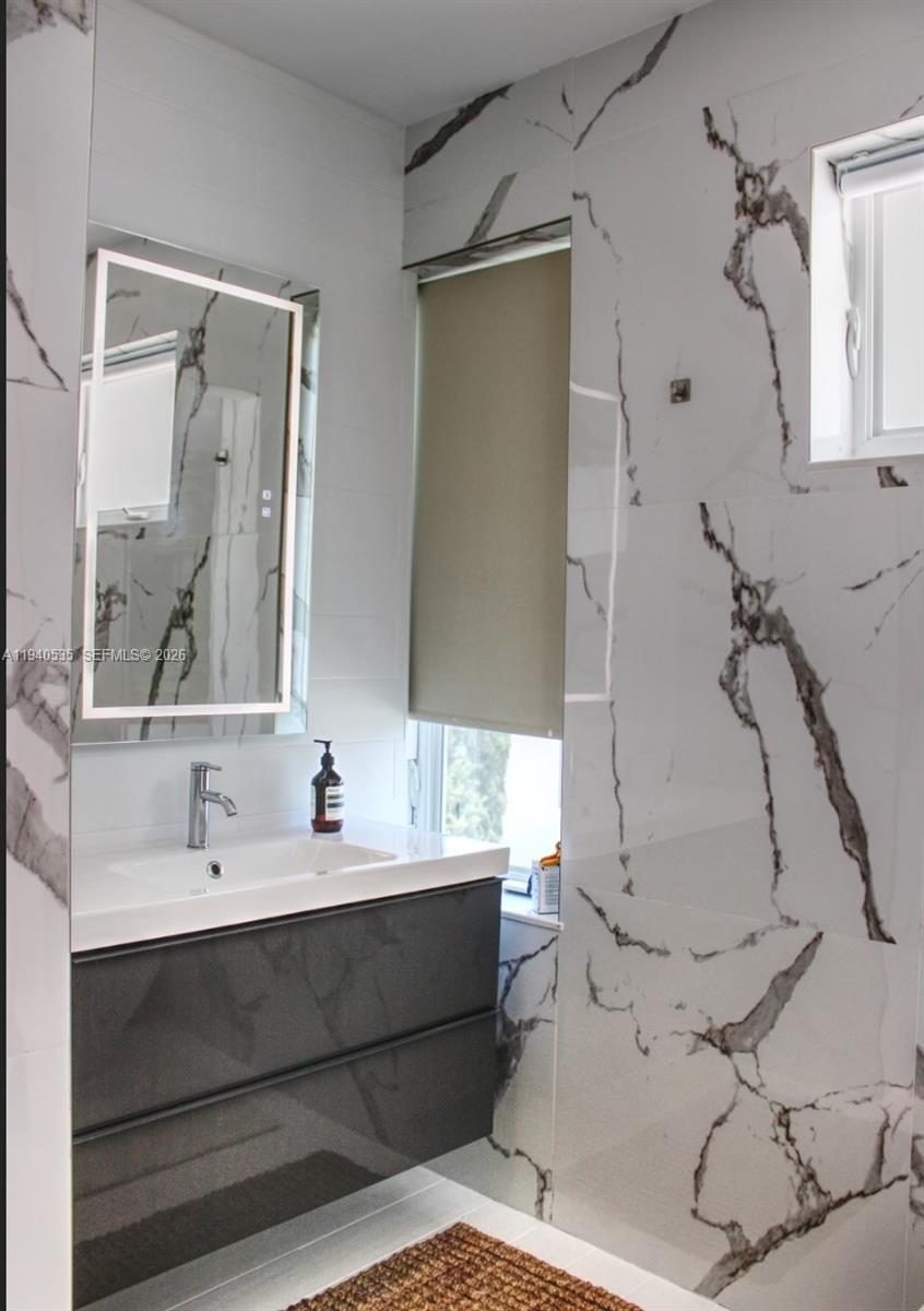 4710 Pine Tree Drive, Unit 49 Miami Beach, FL 33140 - Photo 17 of 26 a bathroom with a double vanity sink mirror and shower