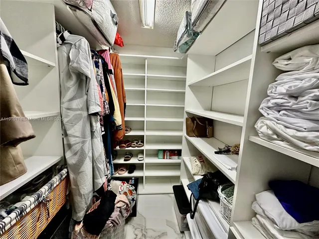 a view of walk in closet with clothes and shoes