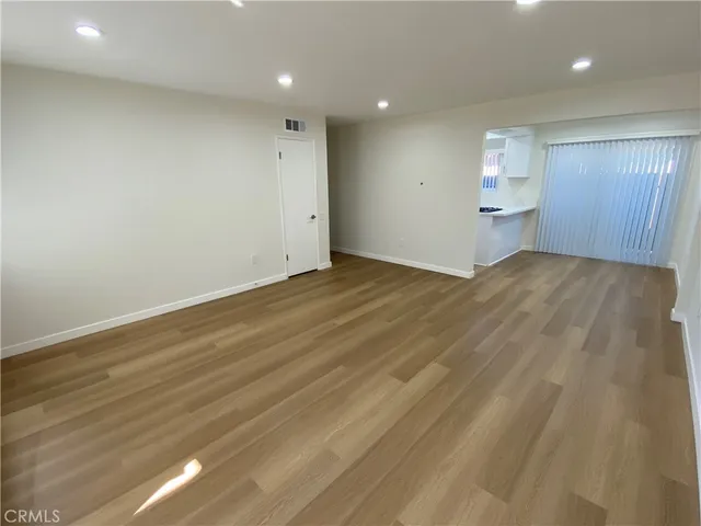a view of empty room with wooden floor and window