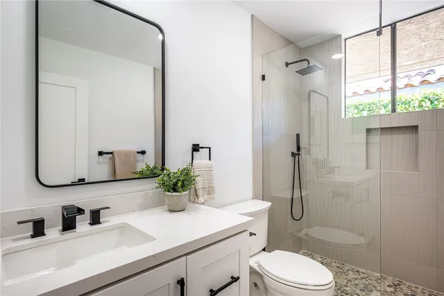a bathroom with a sink toilet mirror and shower