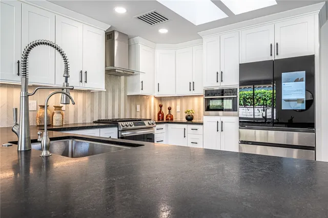 a kitchen with stainless steel appliances granite countertop a stove a sink and a refrigerator with wooden floors