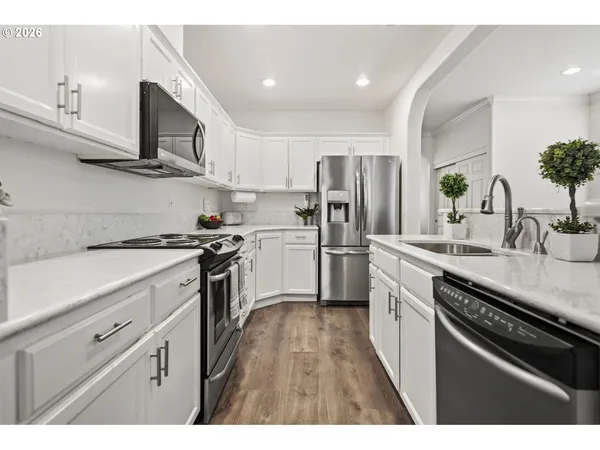 a kitchen with kitchen island granite countertop a sink stainless steel appliances and white cabinets