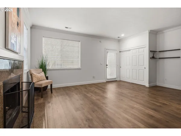 a view of an empty room with a window and wooden floor