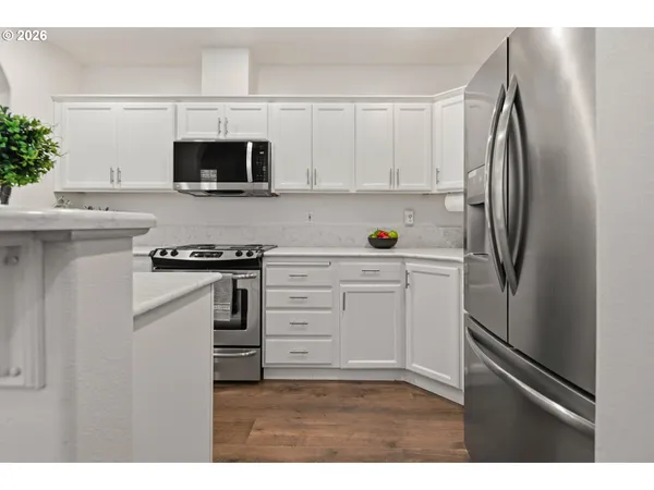 a kitchen with stainless steel appliances a refrigerator stove and white cabinets