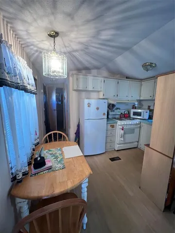 a kitchen with refrigerator and wooden floor