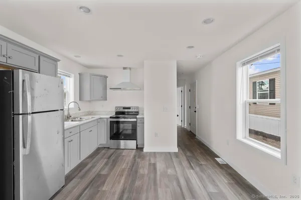 a kitchen with a refrigerator a stove top oven and wooden floor