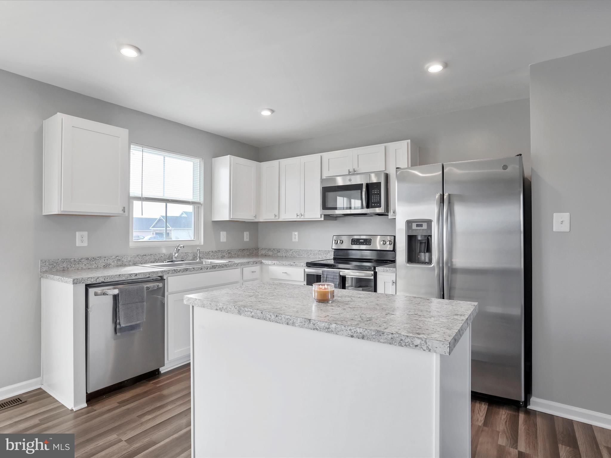 257 Switchgrass Court Bunker Hill, WV 25413 - Photo 3 of 26 a kitchen with kitchen island granite countertop stainless steel appliances a sink a stove a refrigerator cabinets and a center island