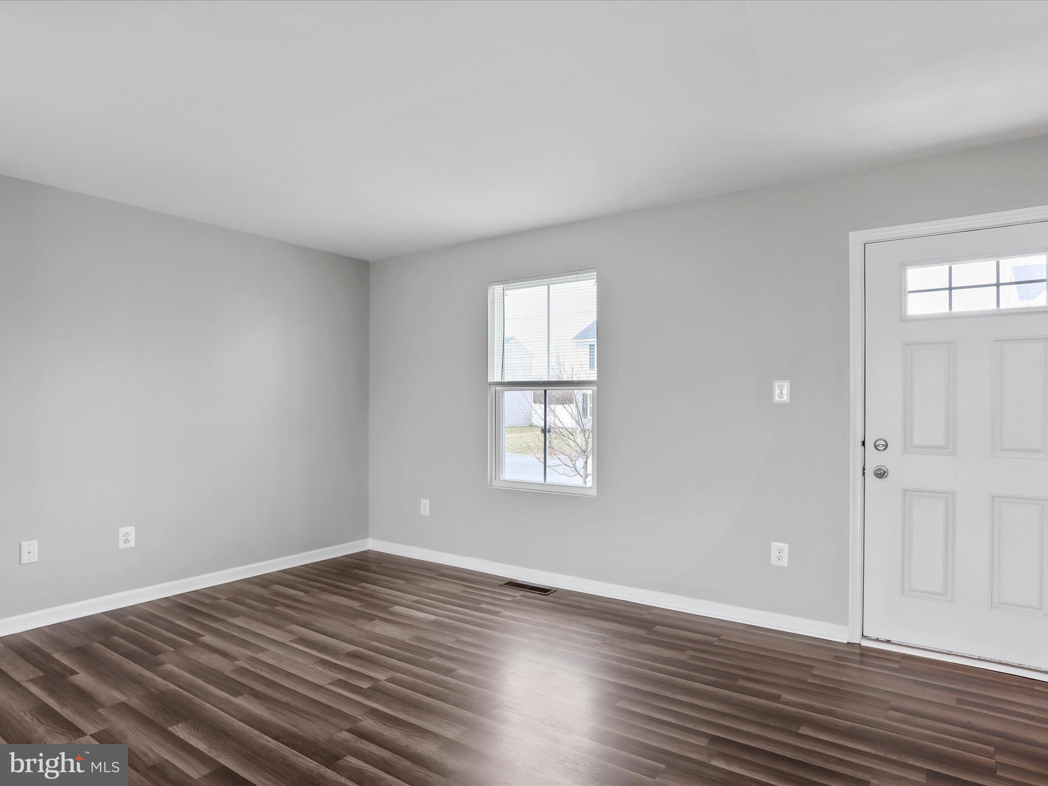 257 Switchgrass Court Bunker Hill, WV 25413 - Photo 7 of 26 a view of an empty room with wooden floor and a window