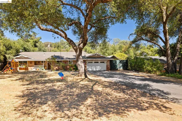 a view of a house with large tree and wooden fence