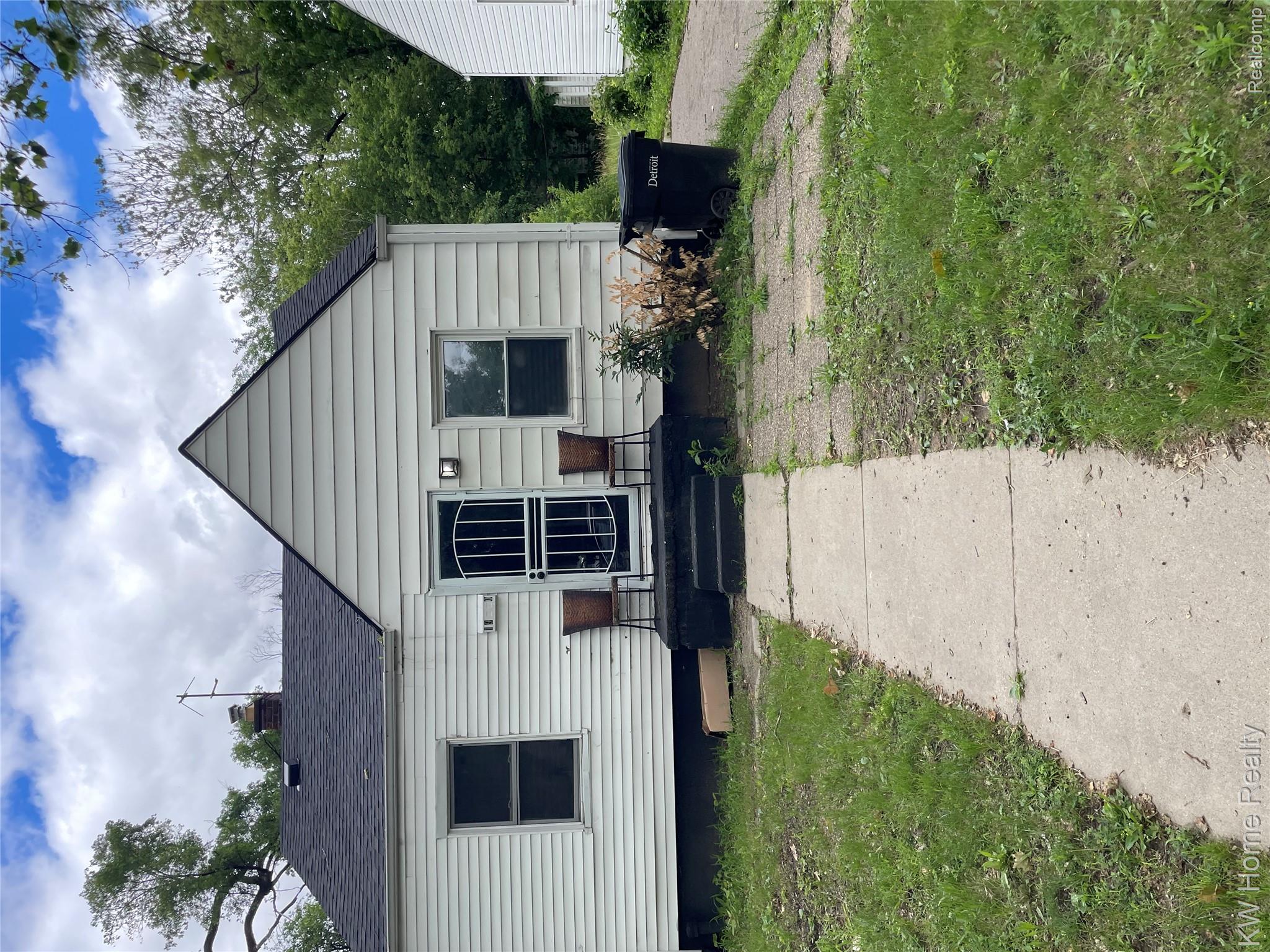 19350 Glastonbury Road Detroit, MI 48219 - Photo 2 of 11 White siding exterior with a dark roof and a front entry with a security screen door