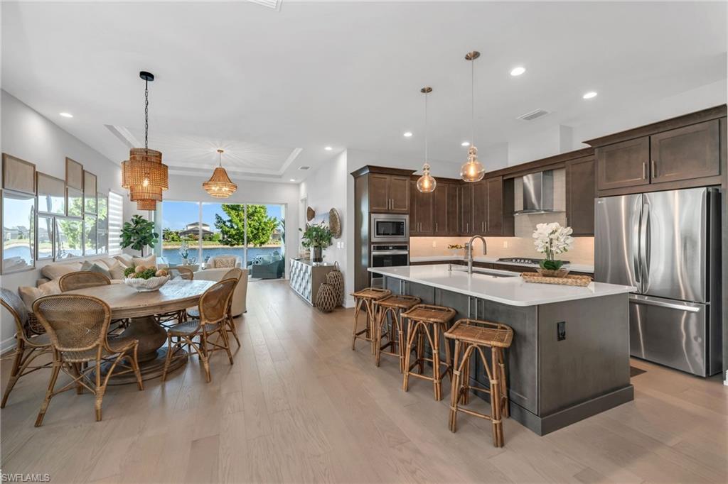 9028 Mayreau Way Naples, FL 34114 - Photo 2 of 24 a kitchen with stainless steel appliances kitchen island granite countertop a table chairs and a refrigerator