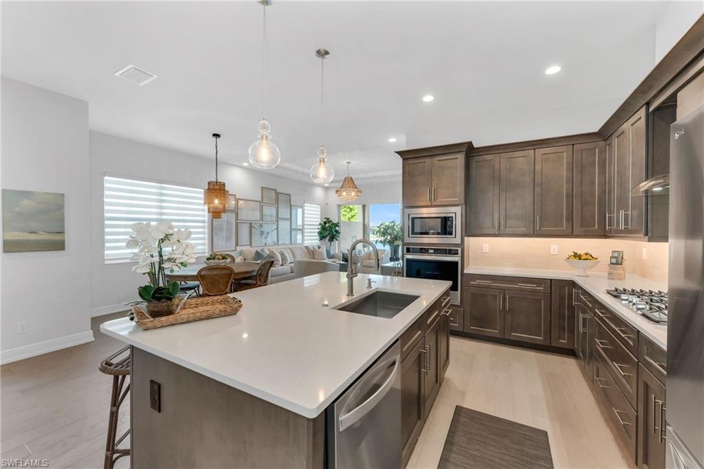 9028 Mayreau Way Naples, FL 34114 - Photo 4 of 24 a kitchen with stainless steel appliances a table and chairs in it