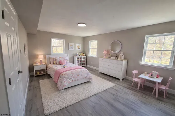 a spacious bedroom with a bed a chandelier and windows