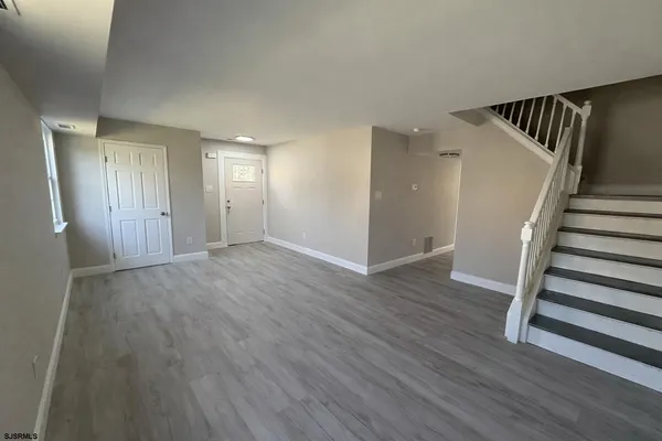 a view of an empty room with wooden floor and stairs