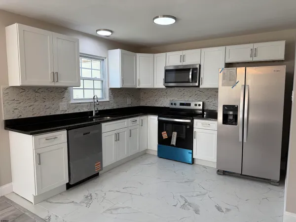 a kitchen with stainless steel appliances granite countertop a sink and a refrigerator