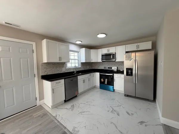 a kitchen with granite countertop a refrigerator sink and cabinets